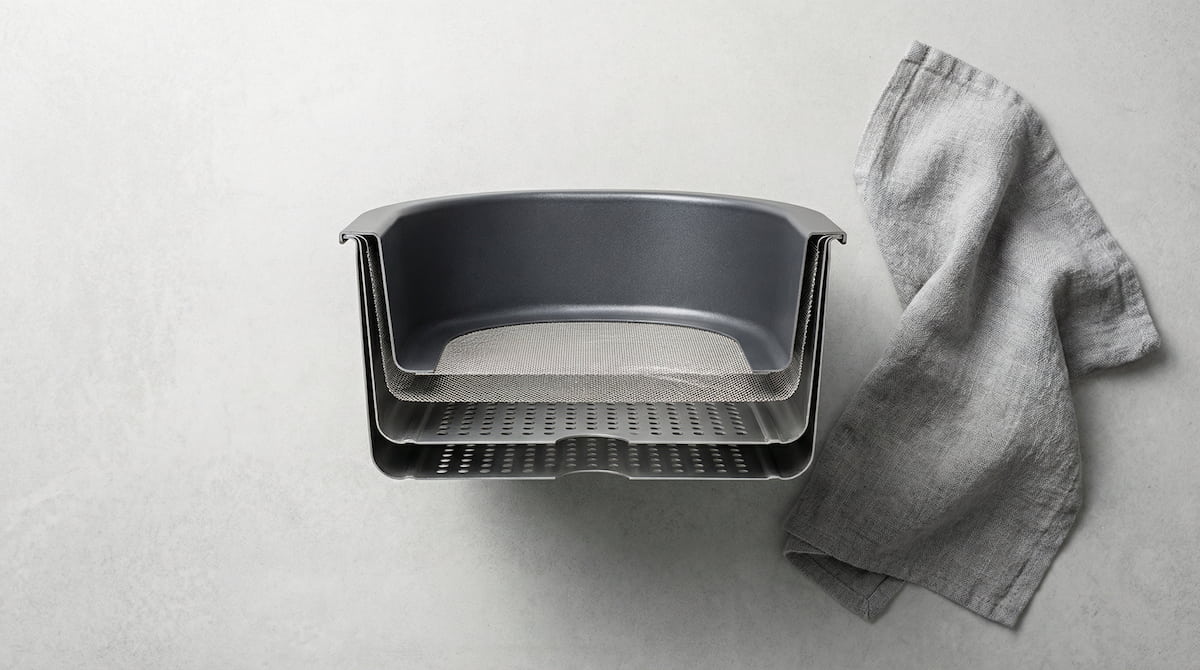 overhead view of air fryer basket showing coating construction on gray concrete surface