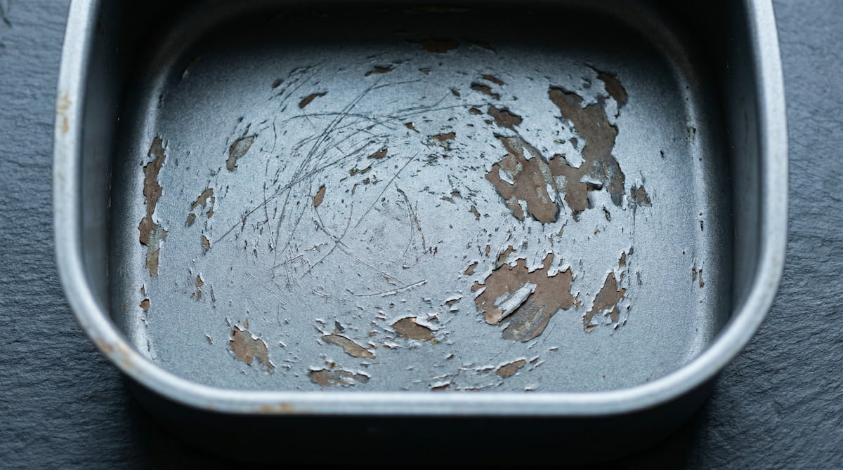 Close-up of worn non-stick air fryer basket coating — visible scratches that signal it is time to replace for safer cooking