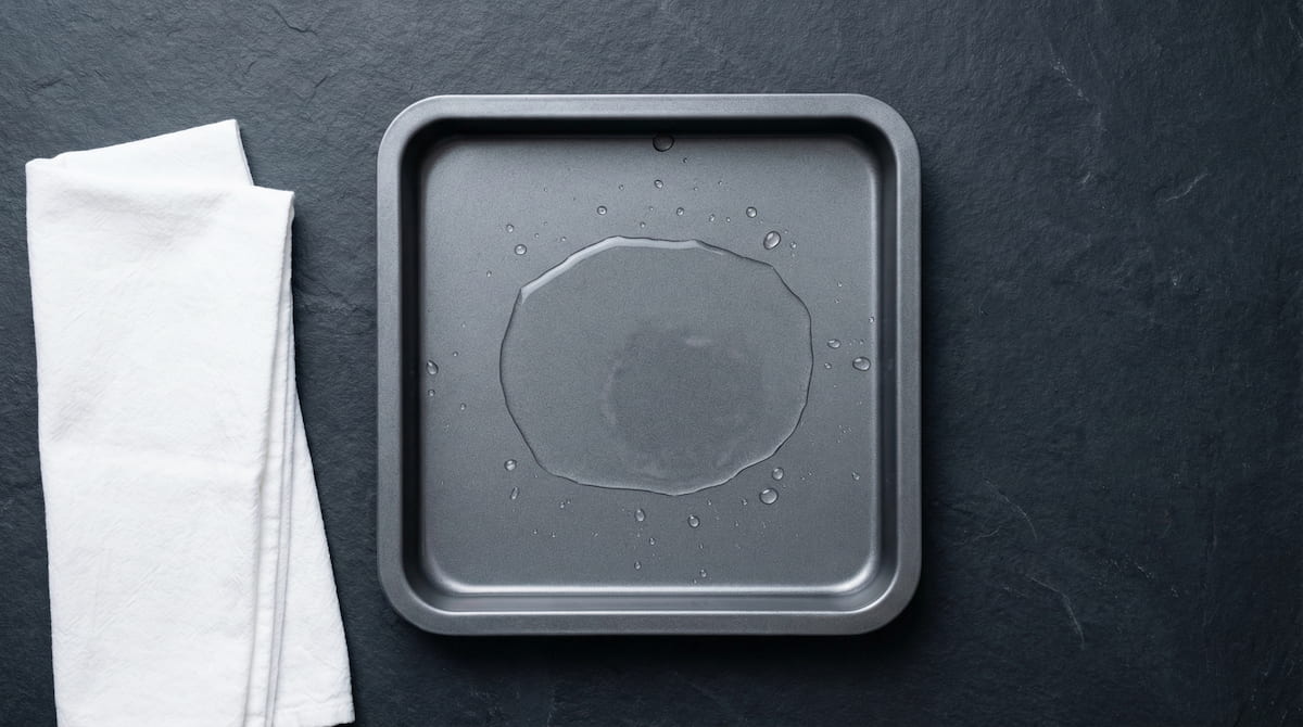 Clean air fryer drip tray with water added to prevent smoke when cooking fatty foods like bacon or chicken