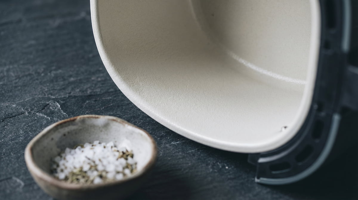 close-up of ceramic-coated air fryer basket on dark slate surface showing PFAS-free cooking interior