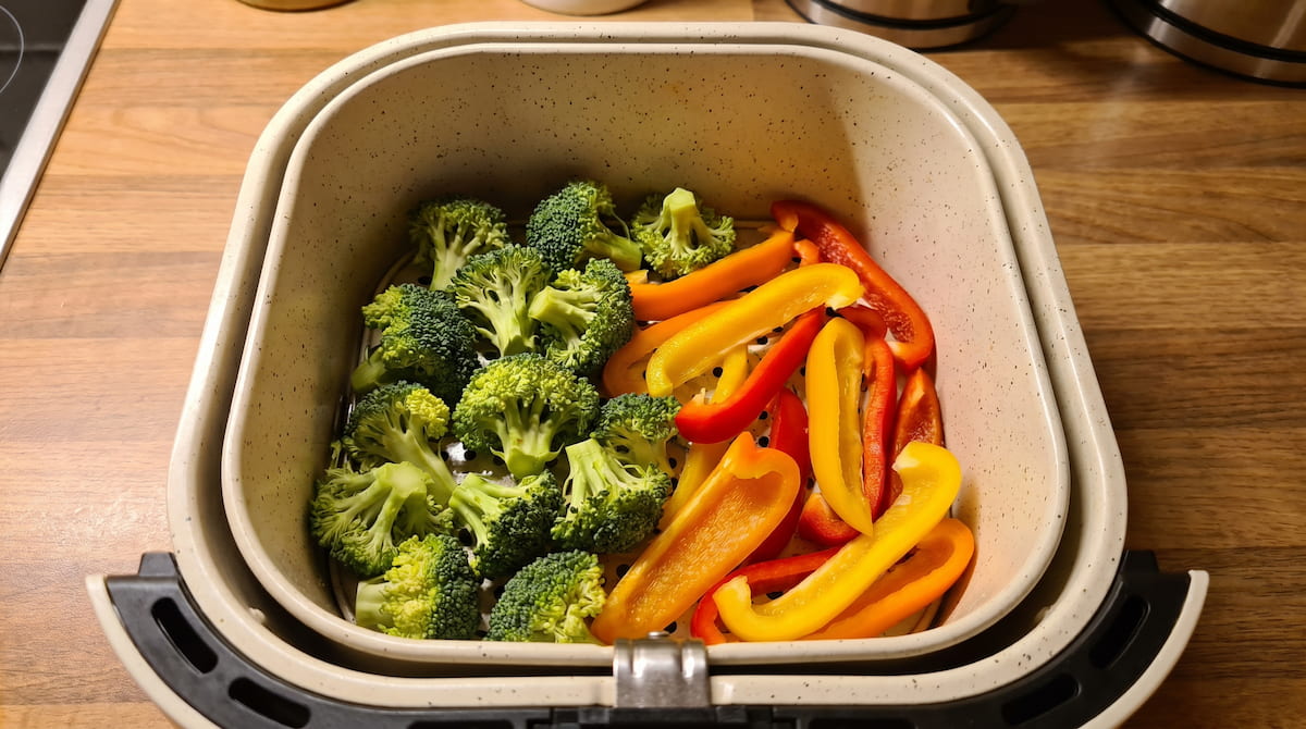fresh vegetables in ceramic air fryer basket ready to cook