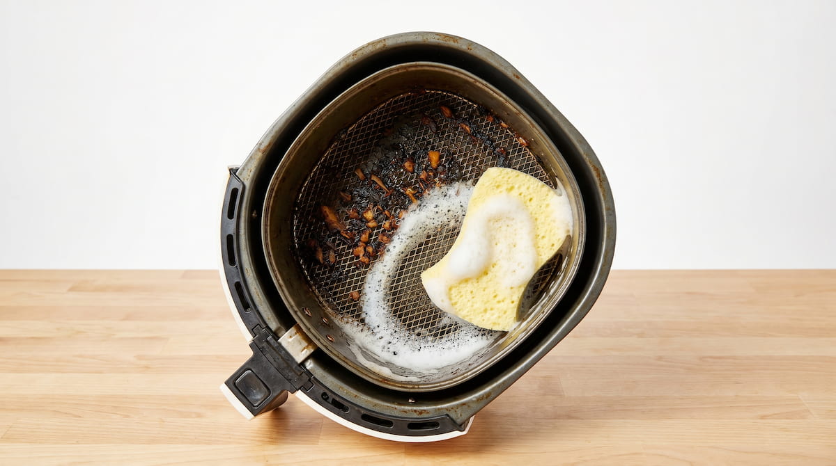scrubbing grease from air fryer basket with soft sponge safely
