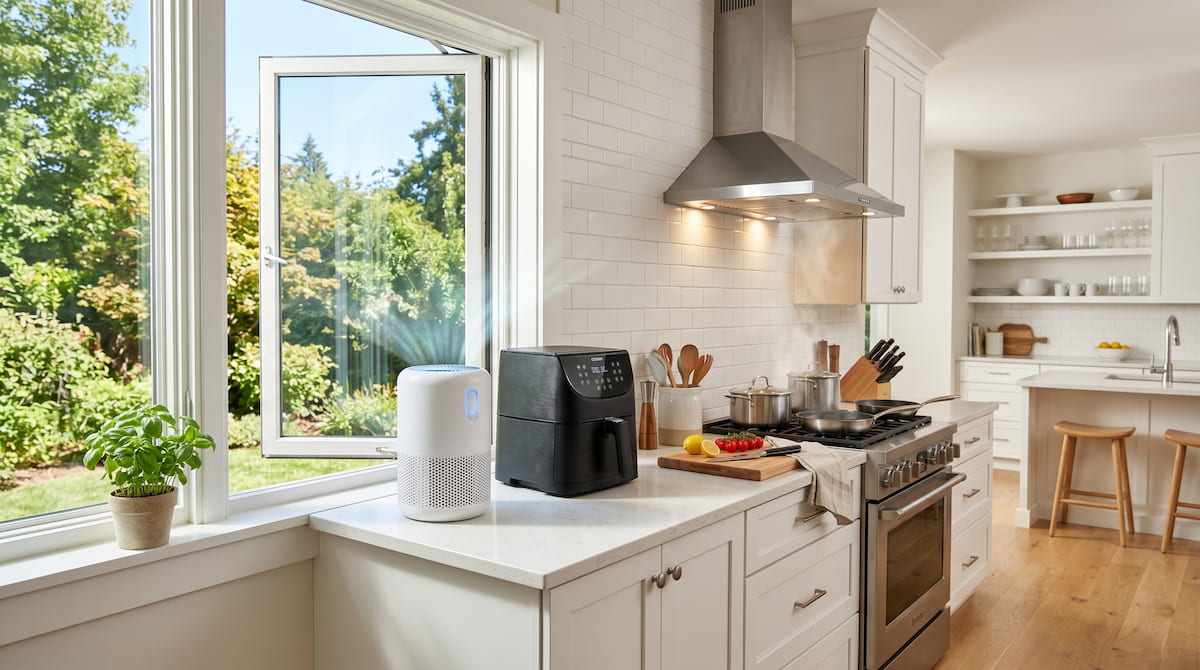 Kitchen with air purifier and open window next to air fryer — ideal setup for indoor air quality