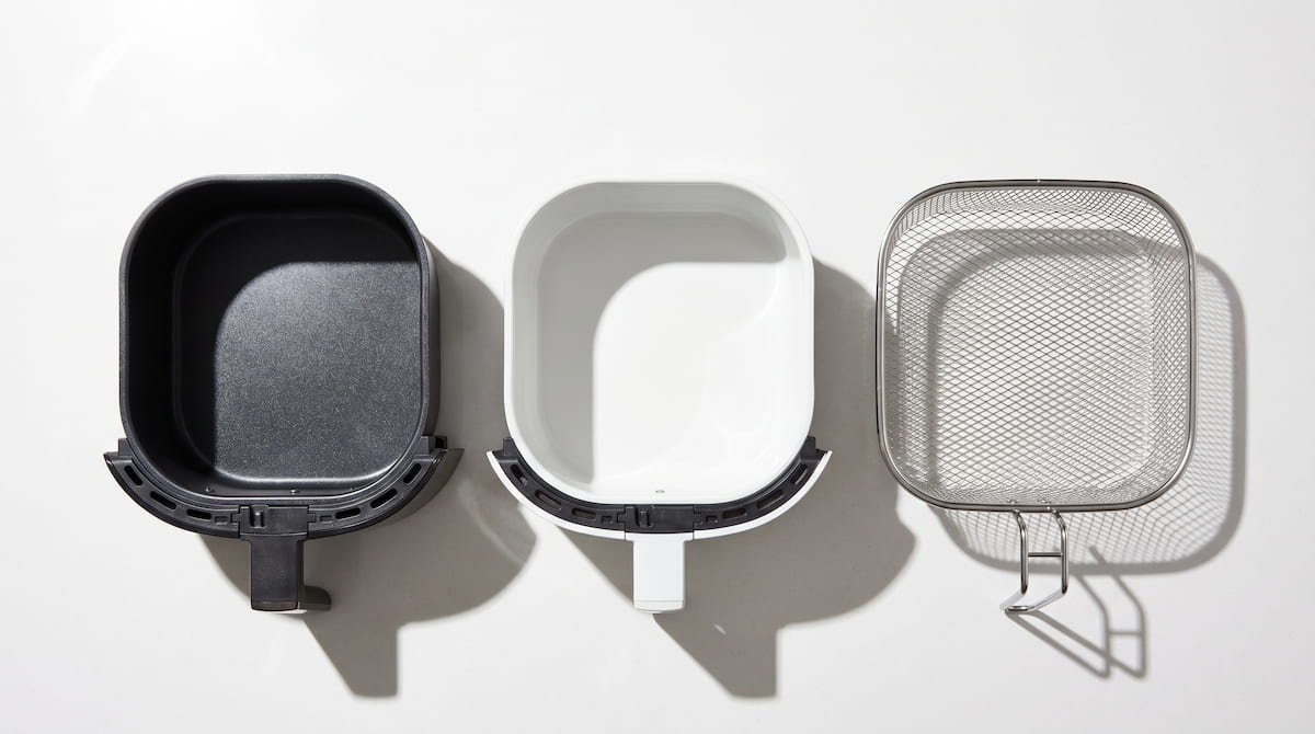nonstick ceramic and stainless steel air fryer basket comparison flat lay