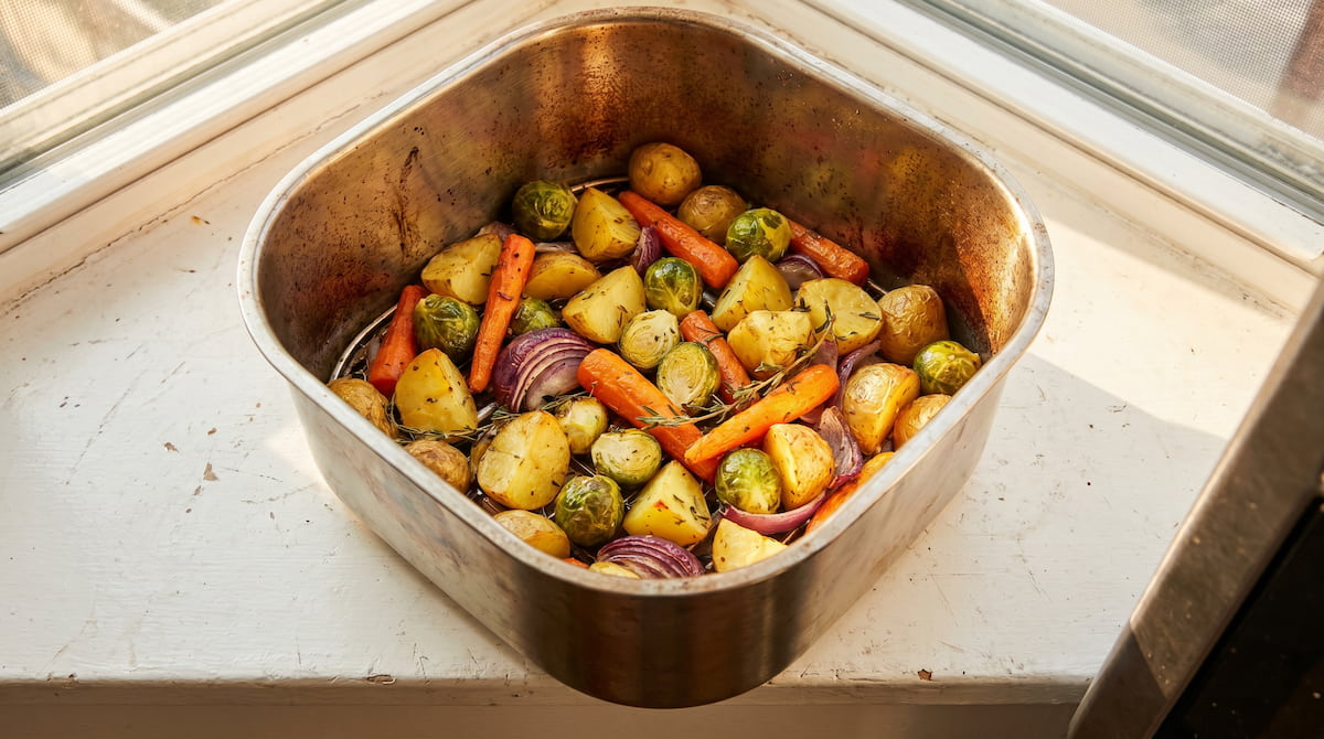 stainless steel air fryer basket with golden roasted vegetables close up
